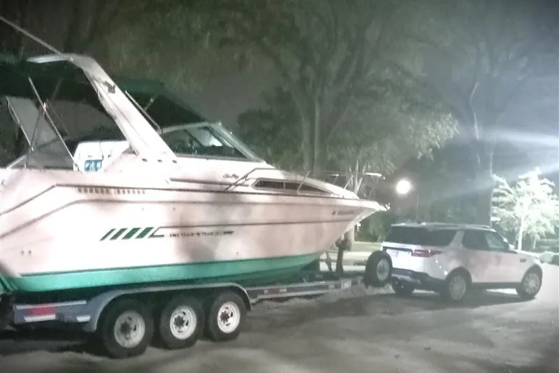 Slide: The Image of 1993 Sea Ray 290 Sundancer boat on trailer, towed by SUV at night. - 5