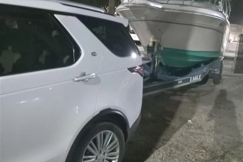 Slide: The Image of White SUV towing a 1993 Sea Ray 290 Sundancer boat on a trailer at night. - 6