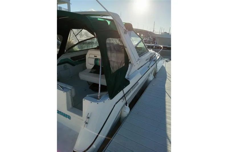 Slide: The Image of 1993 Sea Ray 290 Sundancer docked, featuring green canopy and spacious seating area. - 7