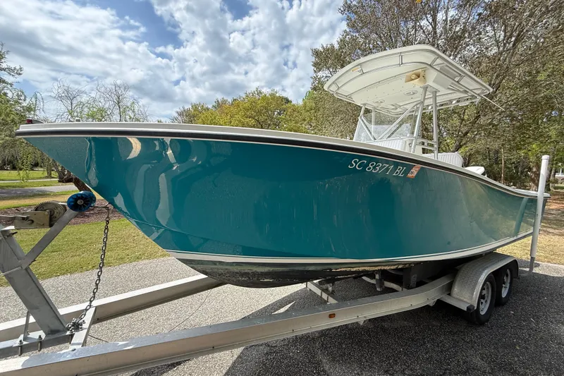 Slide: The Image of 1997 Regulator 23 boat on trailer, teal hull, parked outdoors. - 4
