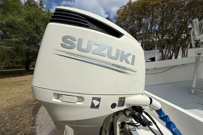 Slide: The Image of Suzuki four-stroke outboard motor on a 1997 Regulator 23 boat, parked outdoors. - 8