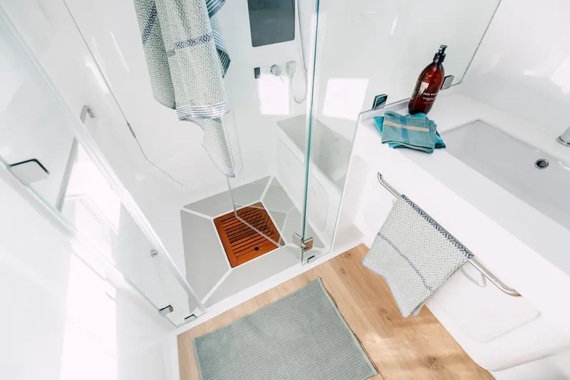 Slide: The Image of Modern bathroom with glass shower, wooden floor, and stylish towels; Vision 444, 2026 model. - 28