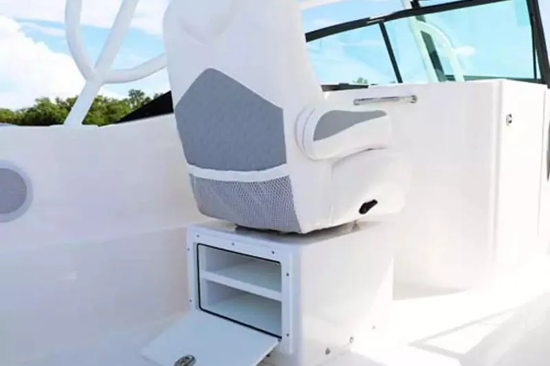 Slide: The Image of 2026 Twin Vee 240 GFX DC boat interior with white captain's chair and storage compartment. - 14