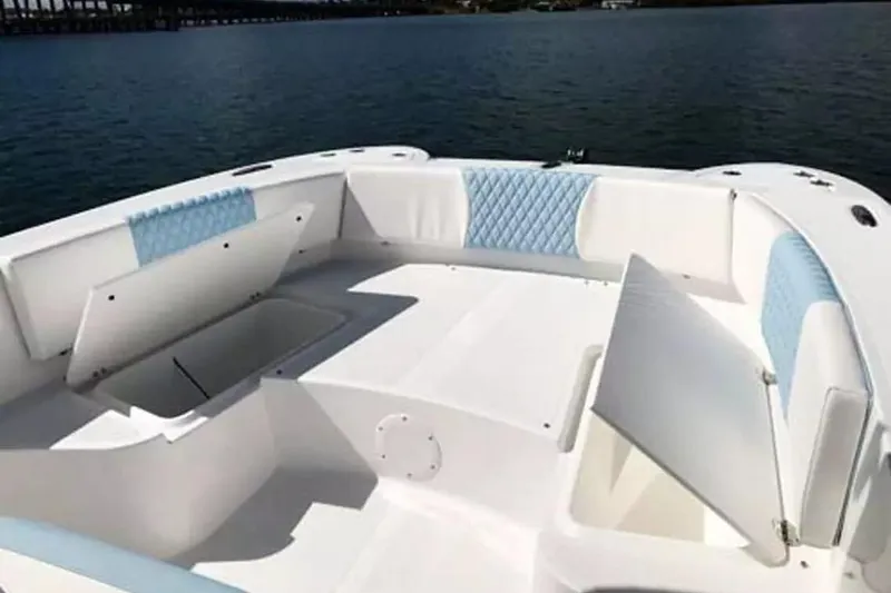 Slide: The Image of 2026 Twin Vee 240 GFX DC boat interior with open storage compartments on calm water. - 19