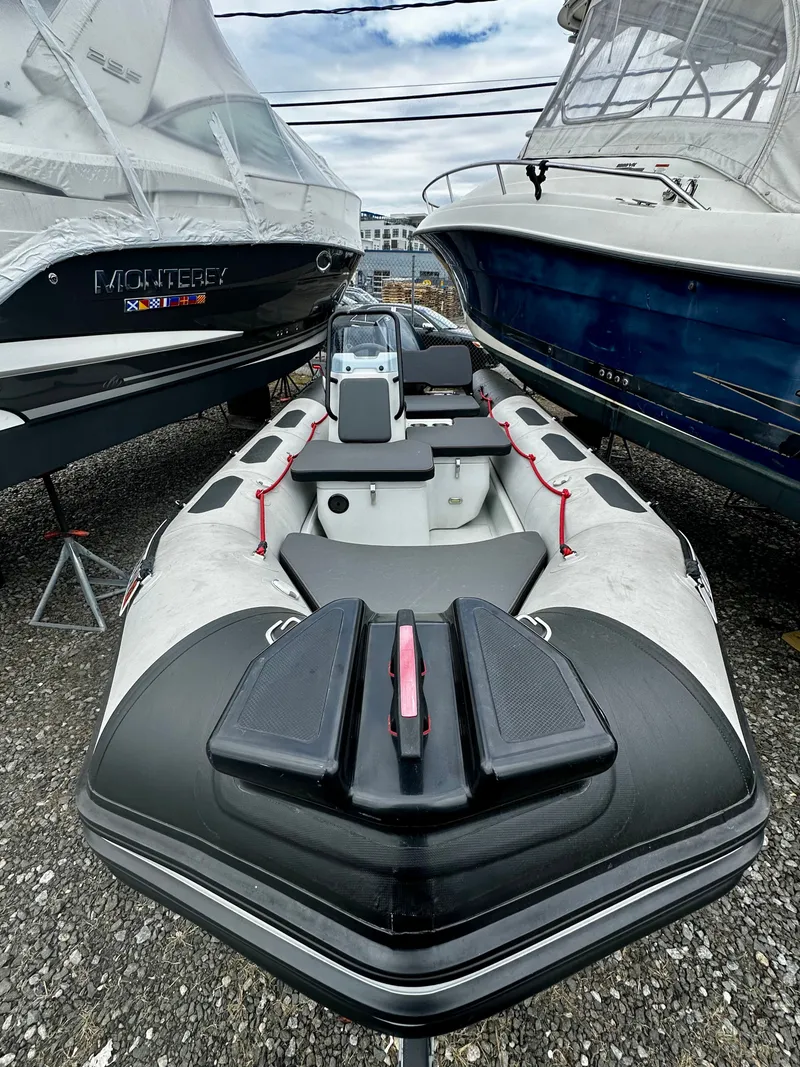 The Image of 2023 Zodiac Open 4.8 inflatable boat between two larger boats. - 1