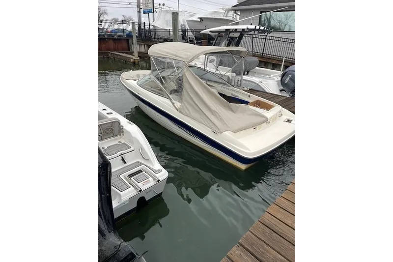The Image of 2003 Bayliner 205 Classic boat docked with protective cover, in a marina setting. - 1
