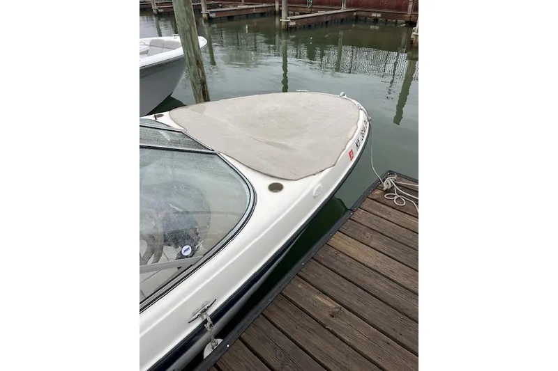 Slide: The Image of 2003 Bayliner 205 Classic boat docked, featuring a covered bow and sleek design. - 11