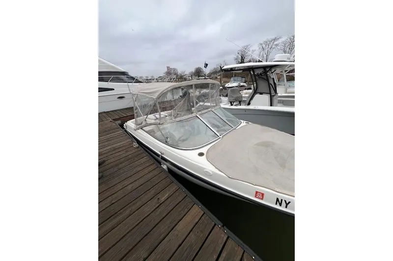 Slide: The Image of 2003 Bayliner 205 Classic boat docked, featuring a clear canopy and sleek design. - 12