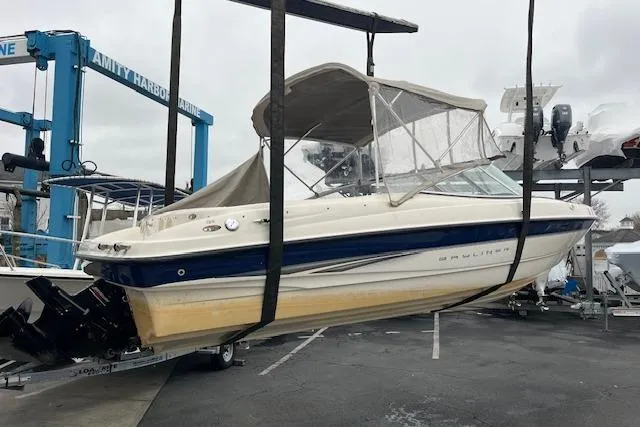 Slide: The Image of 2003 Bayliner 205 Classic boat in a marina lift, featuring a blue and white design. - 13