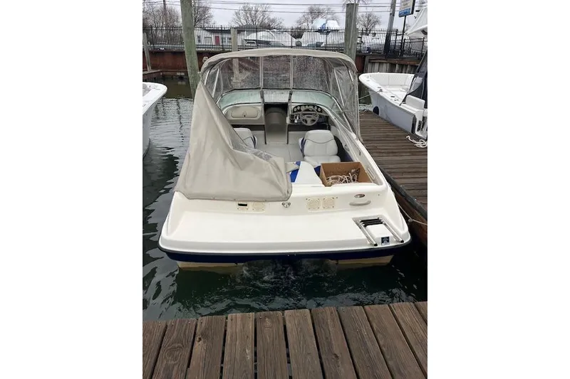 Slide: The Image of 2003 Bayliner 205 Classic boat docked, featuring a covered cockpit and visible interior seating. - 2