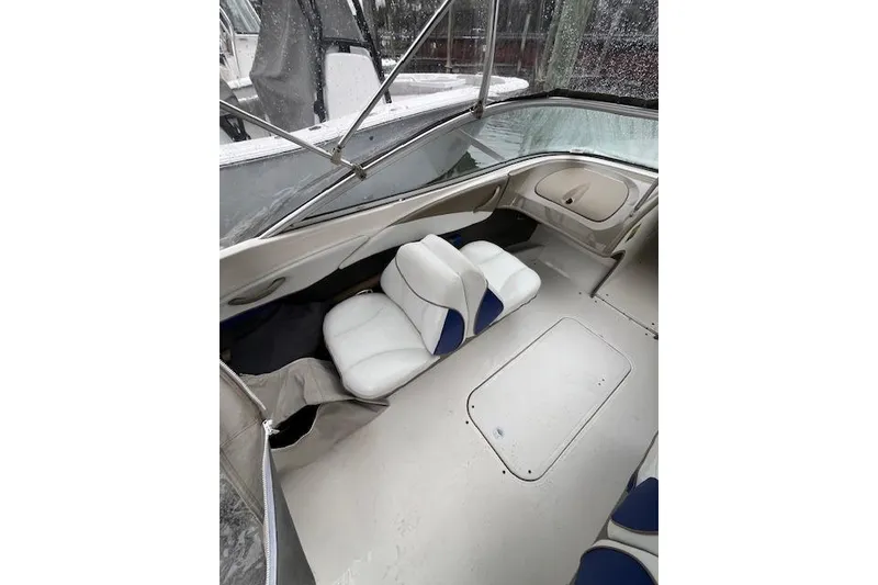 Slide: The Image of 2003 Bayliner 205 Classic boat interior with white and blue seating, under a clear canopy. - 6
