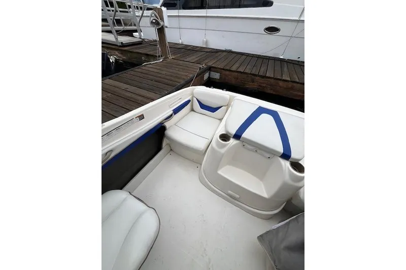 Slide: The Image of 2003 Bayliner 205 Classic boat interior with white and blue seating at dock. - 8