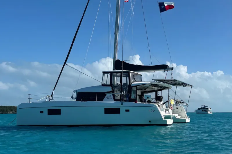 The Image of 2018 Lagoon 42 catamaran anchored in turquoise waters under a clear blue sky. - 0
