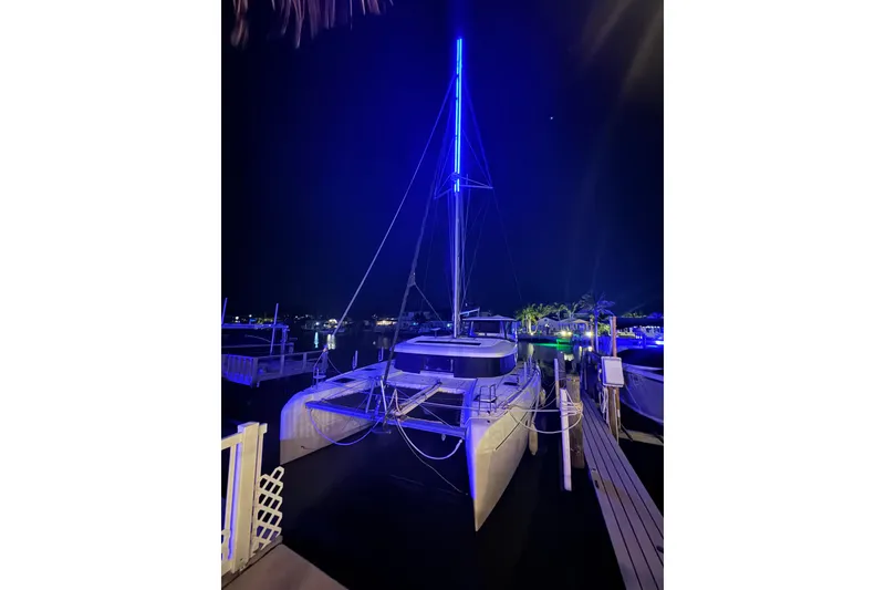 Slide: The Image of 2018 Lagoon 42 catamaran illuminated by blue lights at night in a marina. - 12