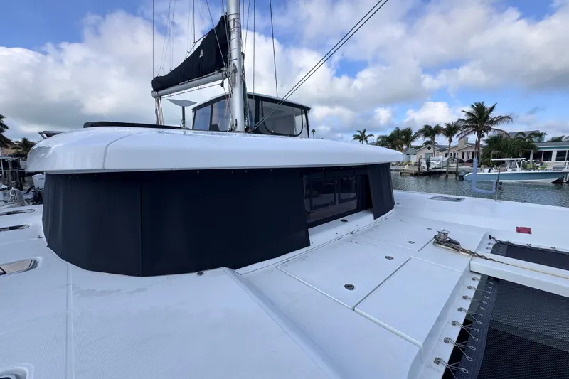Slide: The Image of 2018 Lagoon 42 catamaran docked, showcasing sleek design and spacious deck under a cloudy sky. - 13