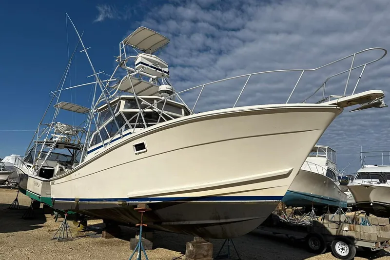 Slide: The Image of 1986 Topaz 32 Express boat on stands, under a partly cloudy sky. - 13