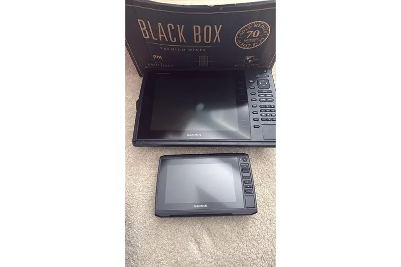 Slide: The Image of Garmin marine electronics on carpet, with Black Box wine packaging in background. - 3