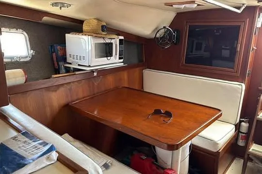 Slide: The Image of 1986 Topaz 32 Express cabin interior with dining area, microwave, and wooden table. - 5