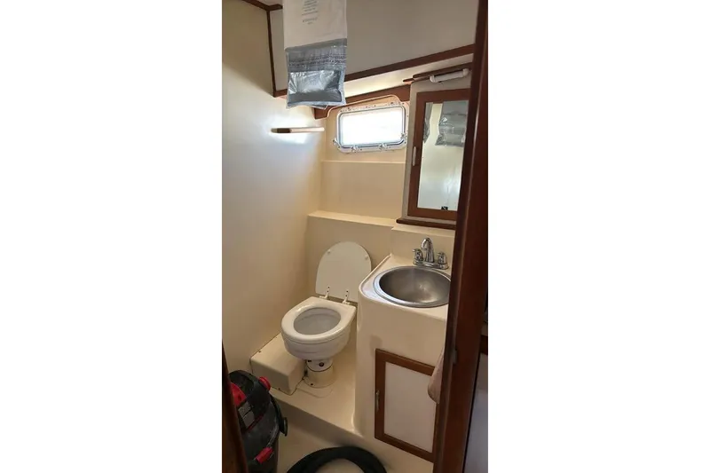 Slide: The Image of 1986 Topaz 32 Express boat bathroom with toilet, sink, mirror, and storage cabinet. - 7