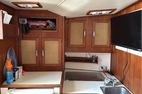 Slide: The Image of 1986 Topaz 32 Express boat interior with wooden cabinets and kitchenette. - 9