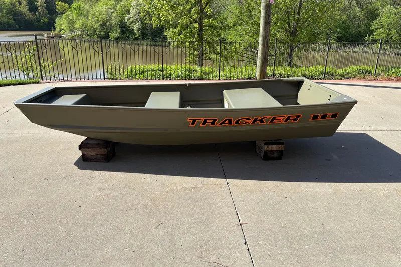 The Image of 2026 Tracker Grizzly 10 Jon boat on concrete near a lake. - 0