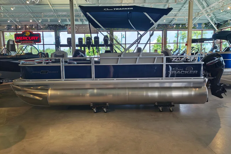 The Image of 2026 Sun Tracker Bass Buggy 18 DLX pontoon boat displayed indoors with Mercury engine. - 1
