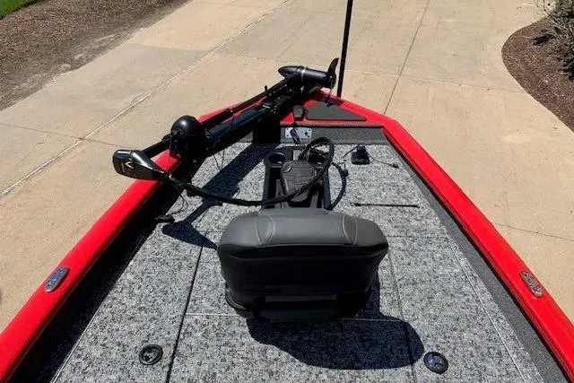 Slide: The Image of 2026 Tracker Pro Team 175 boat with red trim and gray seating on a paved surface. - 20