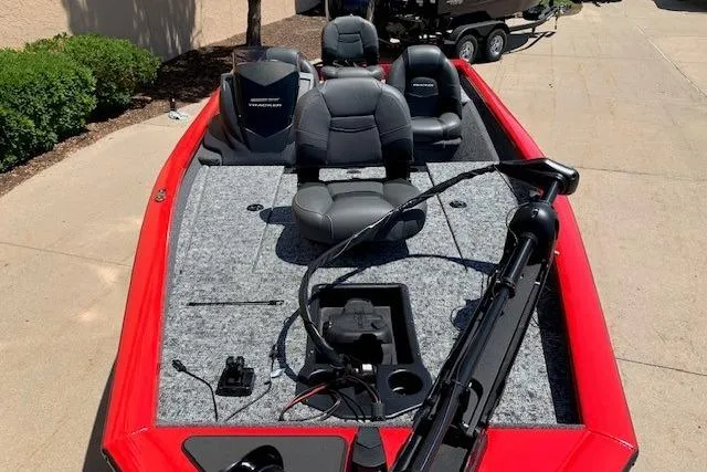 Slide: The Image of 2026 Tracker Pro Team 175 boat with red exterior and gray seating, parked on pavement. - 14