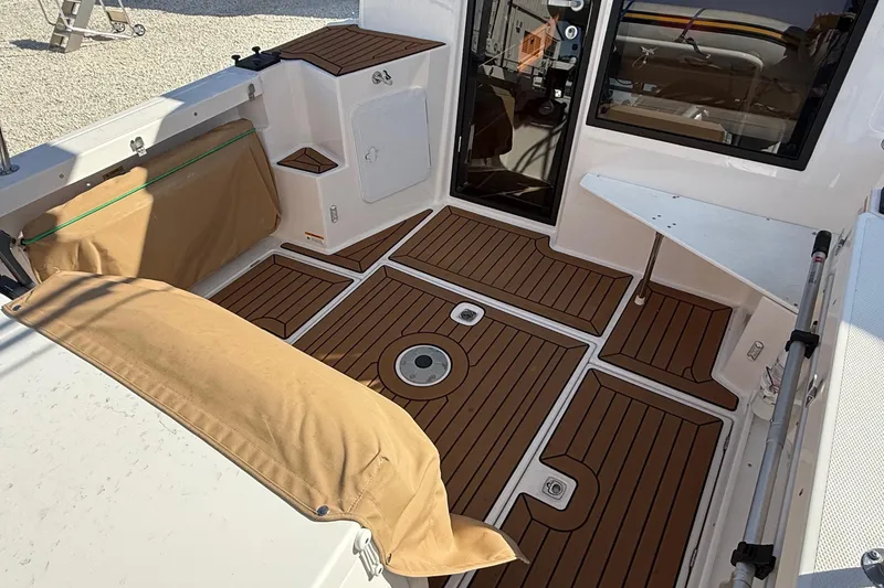 Slide: The Image of 2024 Ranger Tugs R-27 boat interior with teak flooring and beige seating. - 12