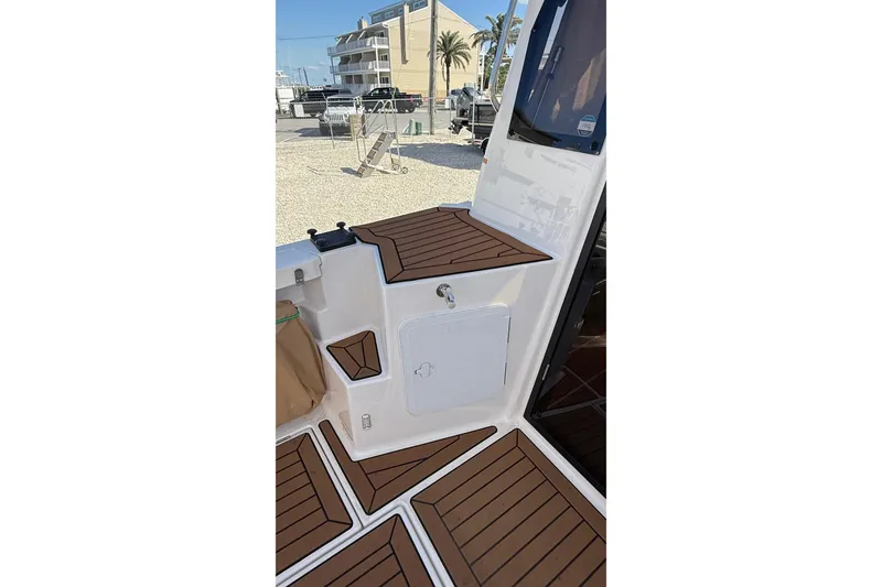 Slide: The Image of 2024 Ranger Tugs R-27 boat interior with teak flooring and outdoor view. - 15