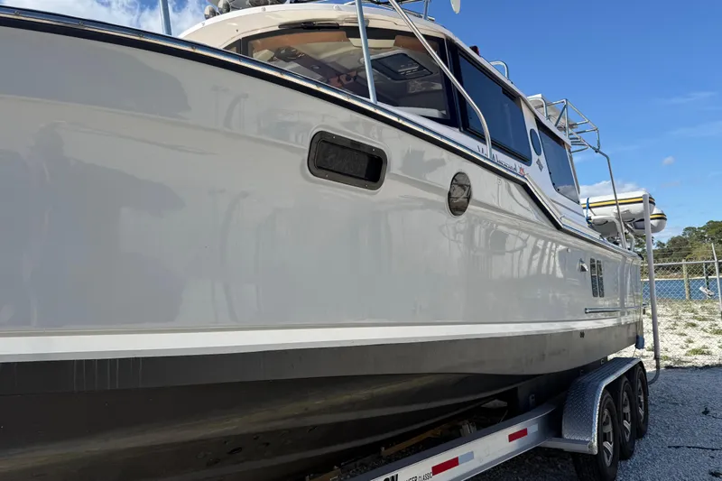 Slide: The Image of 2024 Ranger Tugs R-27 boat on trailer, side view under clear blue sky. - 2