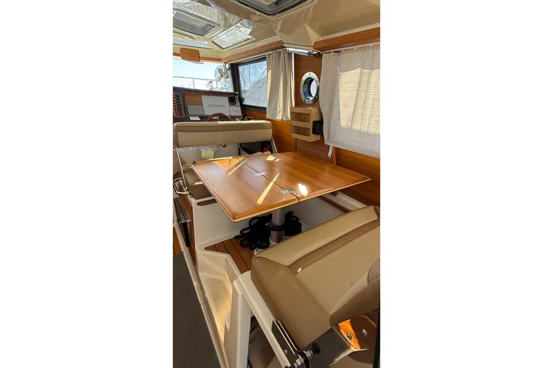 Slide: The Image of 2024 Ranger Tugs R-27 interior with wooden table and beige seating. - 25