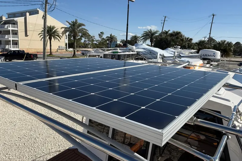Slide: The Image of 2024 Ranger Tugs R-27 with solar panels on deck, docked near palm trees. - 27