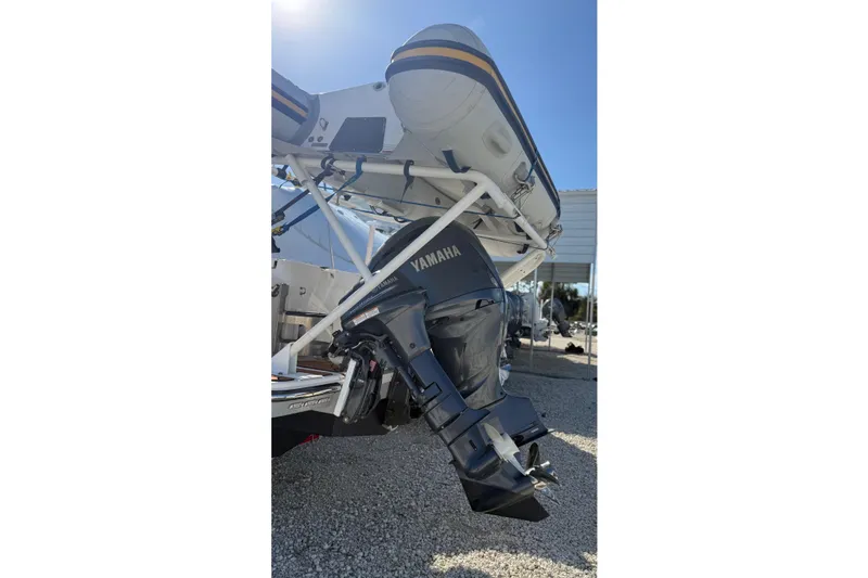 Slide: The Image of 2024 Ranger Tugs R-27 with Yamaha outboard motor and inflatable boat, parked outdoors. - 5