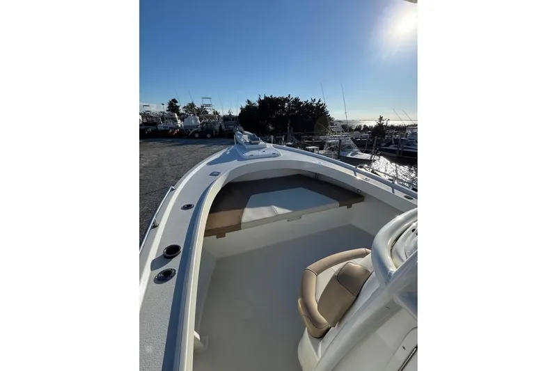 Slide: The Image of 2019 Parker 2501 Center Console boat docked, showcasing spacious deck and seating under clear sky. - 2