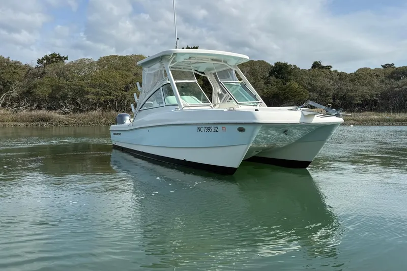 Slide: The Image of 2023 World Cat 230 DC boat on calm water, surrounded by trees. - 3