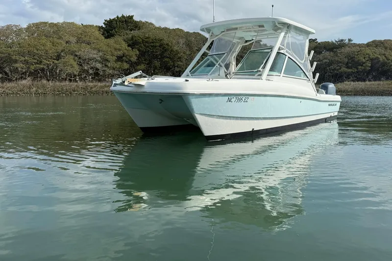 Slide: The Image of 2023 World Cat 230 DC boat on calm water, surrounded by lush greenery. - 5