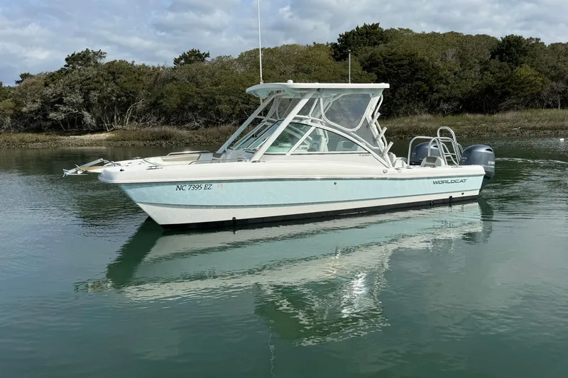 Slide: The Image of 2023 World Cat 230 DC boat on calm water, surrounded by trees. - 6