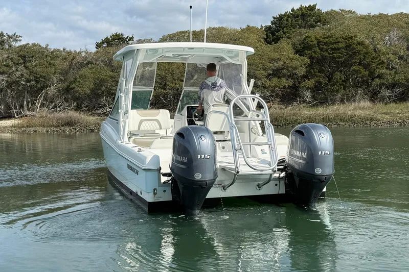 Slide: The Image of 2023 World Cat 230 DC boat with dual Yamaha 115 engines on a calm waterway. - 9