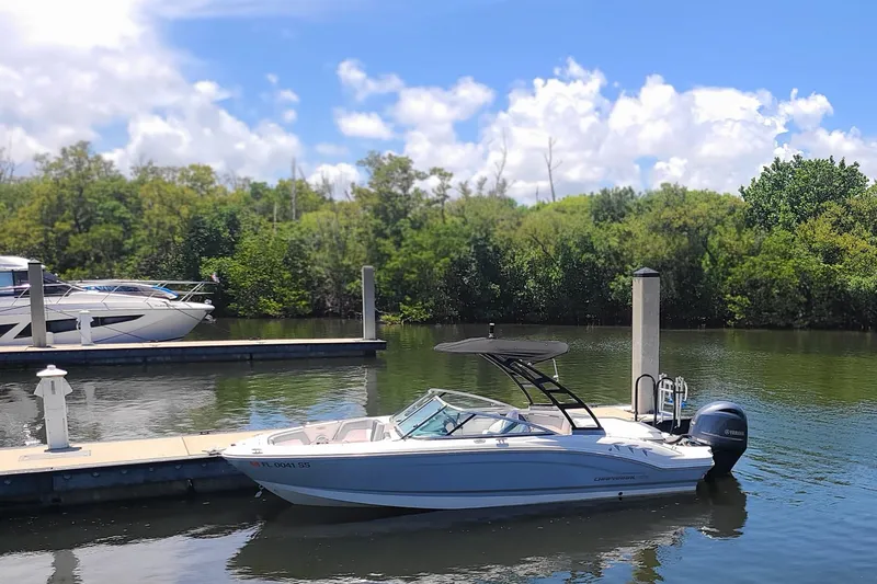 The Image of 2020 Chaparral 21 SSi OB boat docked on a sunny day with lush greenery. - 0