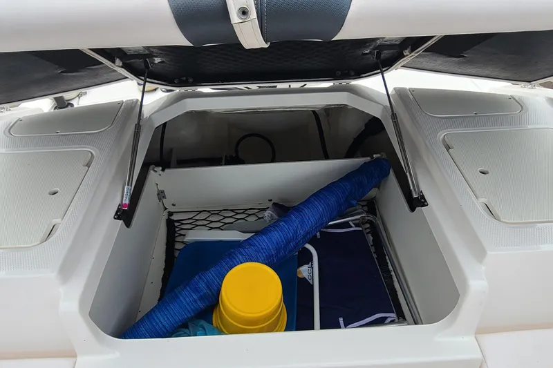 Slide: The Image of Open storage compartment on a 2020 Chaparral 21 SSi OB boat, containing various items. - 15