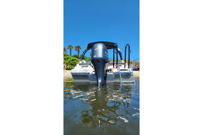 Slide: The Image of 2020 Chaparral 21 SSi OB boat with outboard motor, docked near a sandy beach. - 9
