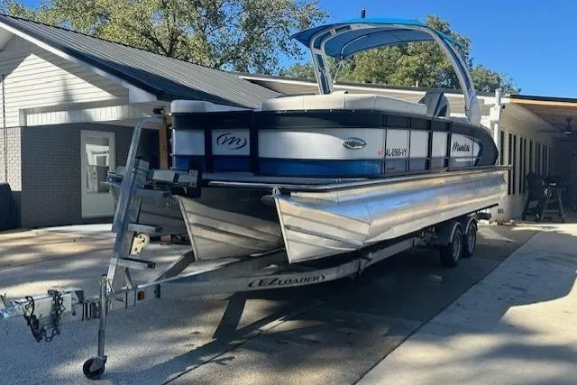The Image of 2020 Manitou 25 X-Plode RFW pontoon boat on trailer, parked near a house. - 0