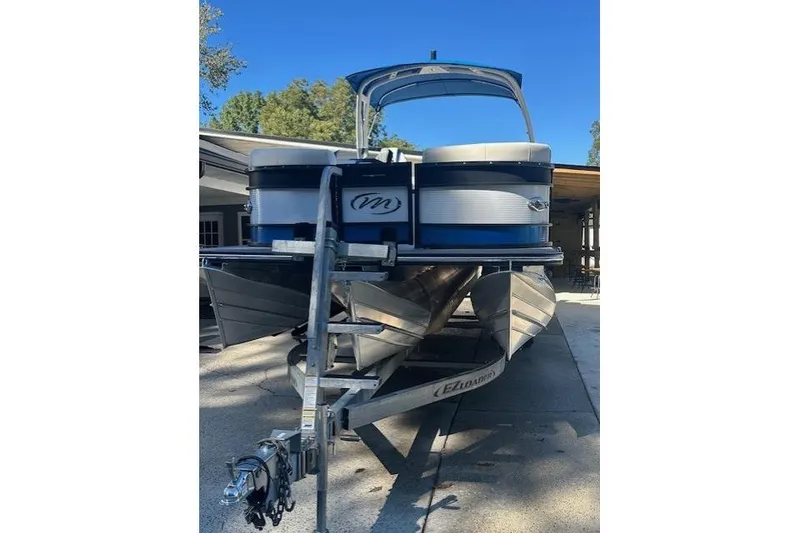 Slide: The Image of 2020 Manitou 25 X-Plode RFW pontoon boat on trailer, parked outdoors. - 11