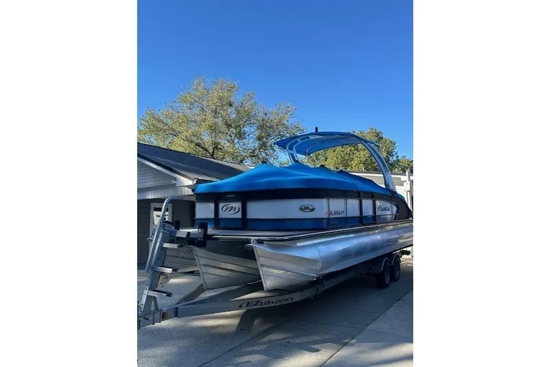 Slide: The Image of 2020 Manitou 25 X-Plode RFW pontoon boat on trailer, blue cover, sunny day. - 3