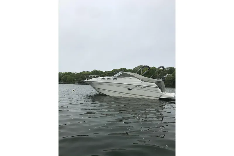 Slide: The Image of 2001 Regal Commodore 2660 boat anchored on calm water with trees in the background. - 10