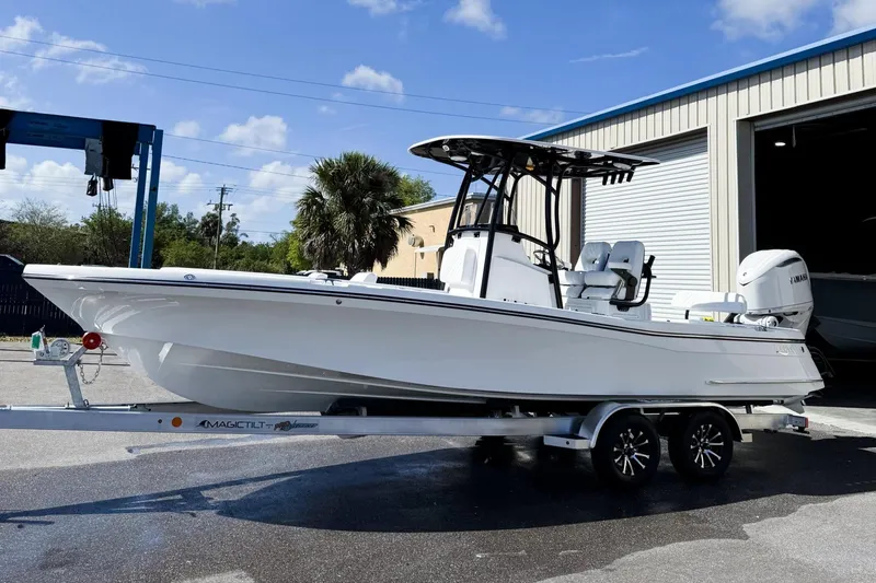 Slide: The Image of 2026 BlackJack 256 Coastal boat on trailer, parked outside a garage under a clear sky. - 0