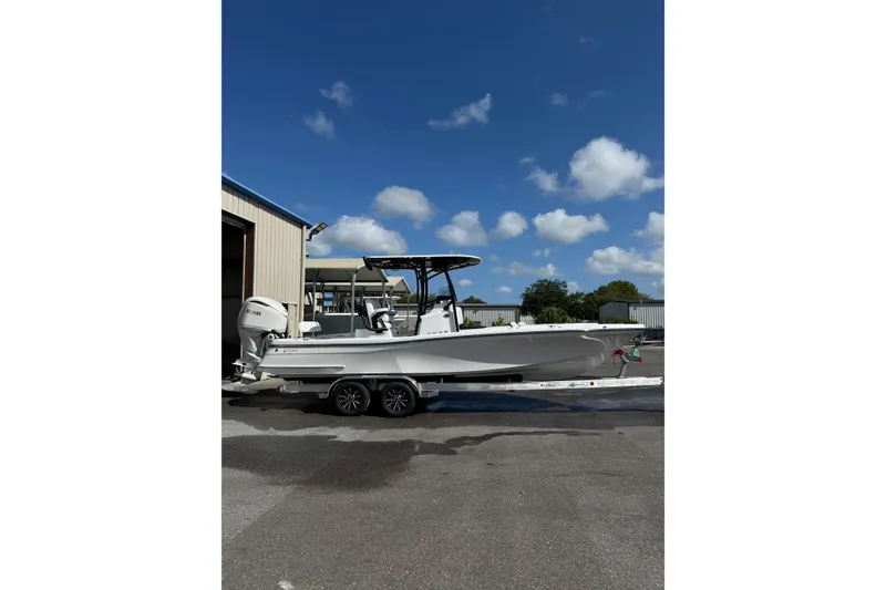 Slide: The Image of 2026 BlackJack 256 Coastal boat on trailer, parked outside a garage. - 1
