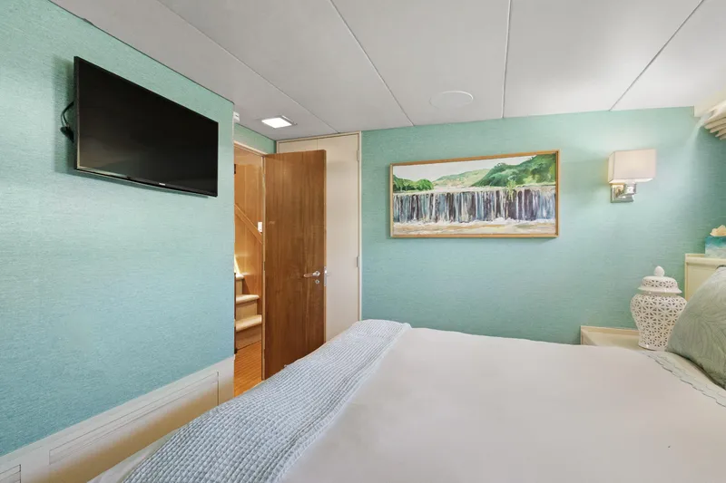 Slide: The Image of Bedroom interior with teal walls, wall-mounted TV, and waterfall painting, aboard a 1985 Burger yacht. - 20