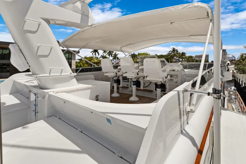 Slide: The Image of Luxury yacht deck with helm station, featuring white seating and canopy, surrounded by tropical scenery. - 37